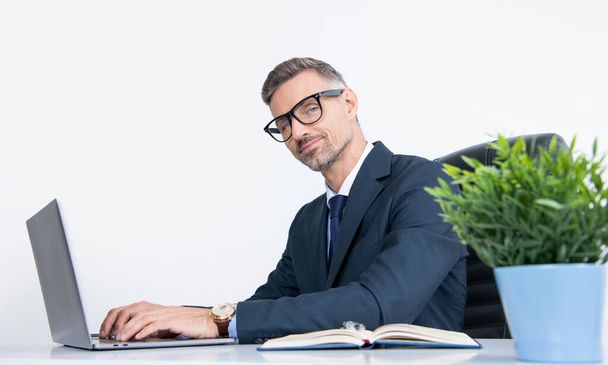 smiling mature businessman sitting in business office with laptop. - Φωτογραφία, εικόνα