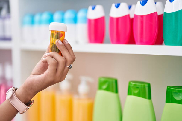 Jeune belle hispanique femme client tenant étiquette pilules à la pharmacie - Photo, image