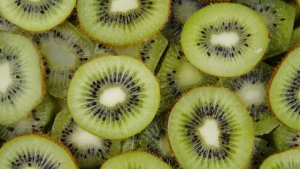 Zielone plastry owoców Kiwi powoli obracające się na czarnym tle. Świeże i soczyste - Materiał filmowy, wideo