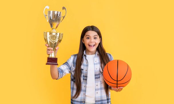 amazed teen champion girl on background. photo of teen champion girl with basketball ball. teen champion girl isolated on yellow. teen champion girl in studio. - 写真・画像