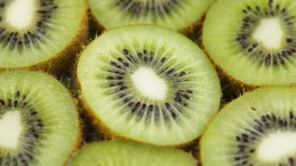 Zielone plastry owoców Kiwi powoli obracające się na czarnym tle. Świeże i soczyste - Materiał filmowy, wideo
