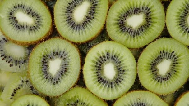 Grüne Kiwi-Fruchtscheiben rotieren langsam auf schwarzem Hintergrund. Frisch und saftig - Filmmaterial, Video