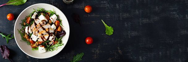Frischer Salat mit Hühnchen, Tomaten, Kräutern und Feta-Käse. Gesunde Ernährung. Ansicht von oben - Foto, Bild