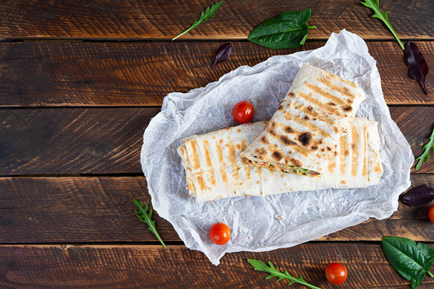 Delicious chicken shawarma sandwich with salad and cheese on wooden background - Photo, Image