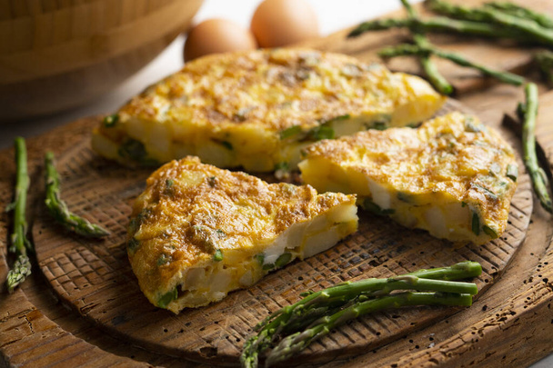 Spanish omelette with green asparagus is an omelette to which chopped potatoes are added. It is one of the best-known and most emblematic dishes of Spanish cuisine - Photo, Image