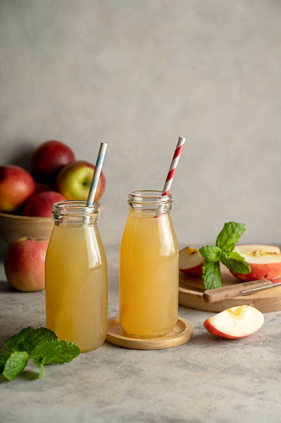 Apple juice glass bottles, with fresh red apples, wooden background - Fotografie, Obrázek
