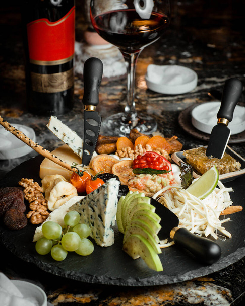 Many different varieties of cheese, dried fruits, fruits, nuts and honey with a smoke effect on the table - Foto, immagini