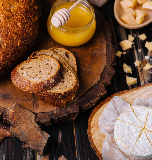 хлеб с медом, грецким орехом и сыром на деревянном пне - Фото, изображение