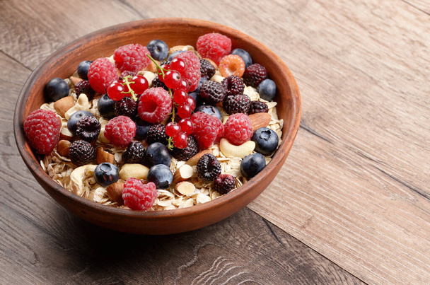 Oatmeal oats with berries and nuts on wooden table - Foto, immagini