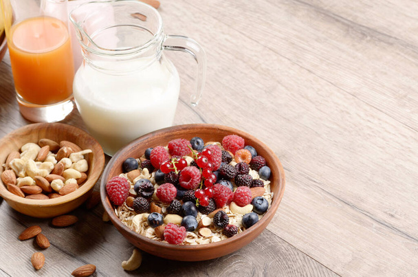 Oatmeal oats with berries nuts orange juice and yogurt on wooden table - Foto, Bild