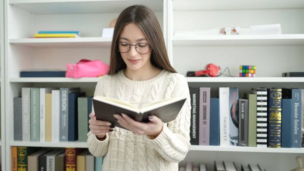 Молода красива іспаномовна жінка стоїть читати книгу в бібліотечному університеті
 - Фото, зображення