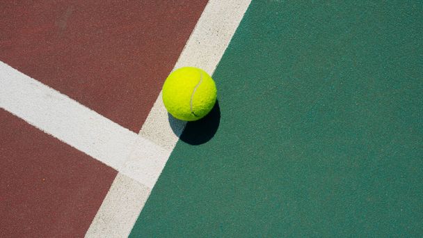 Yellow tennis ball lying on line of the red and green court. Flat lay view. Space for text - Photo, Image
