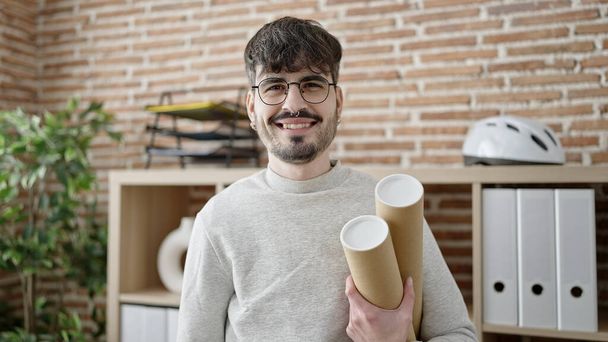 Young hispanic man architect holding blueprints at office - Foto, Bild
