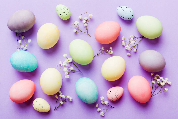 Feliz composición de Pascua. Huevos de Pascua sobre mesa de colores con gypsophila. Huevos coloridos teñidos naturales vista superior de fondo con espacio de copia. - Foto, Imagen