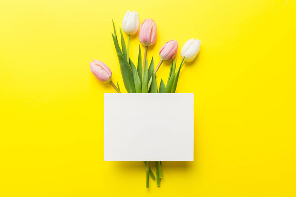 Композиція з порожньою карткою і красивими квітами тюльпанів на кольоровому фоні. вид зверху з простором для вас
. - Фото, зображення