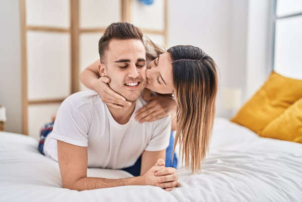 Man and woman couple lying on bed hugging each other and kissing at bedroom - Φωτογραφία, εικόνα