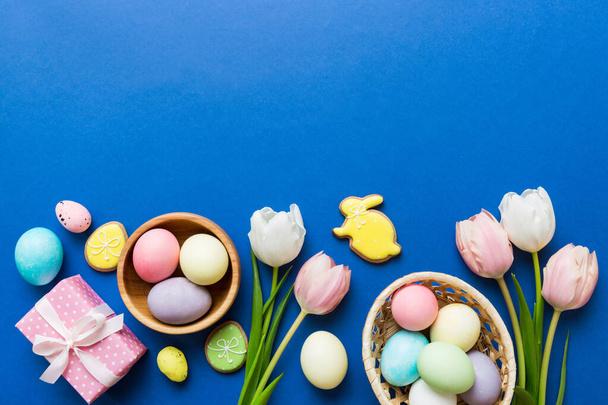 Wielkanoc ramka z jajkami, pudełko z prezentami i tulipan na kolorowym tle. Minimalna koncepcja. Top view Szczęśliwej kompozycji wielkanocnej. Karta z kopią miejsca na tekst. - Zdjęcie, obraz
