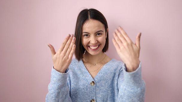 Young beautiful hispanic woman smiling confident asking for home over isolated pink background - Фото, изображение