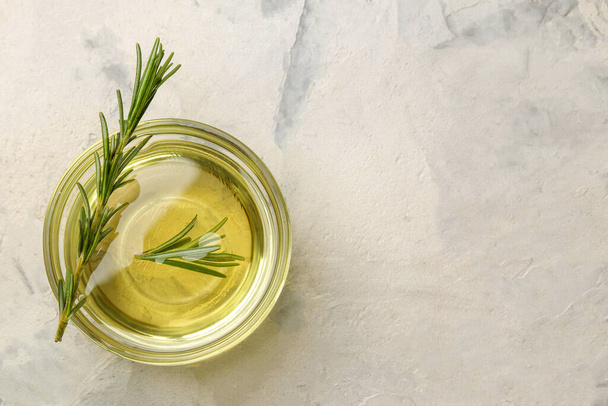 Natural rosemary essential oil in a glass bottle and a fresh sprig of rosemary on a light background. face and body skin care. spa. - Foto, immagini