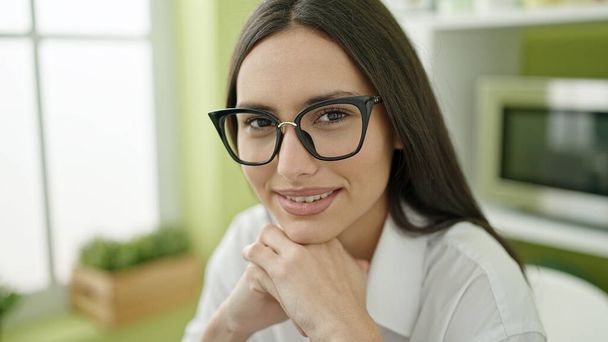 Young beautiful hispanic woman smiling confident sitting on table at dinning room - Photo, Image