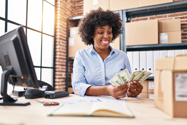 African american woman ecommerce business worker counting dollars at office - Foto, imagen