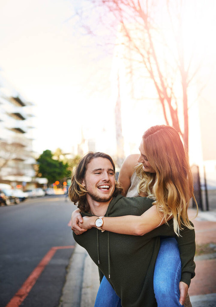 Apanhei-te, querida. um jovem casal feliz desfrutando de um passeio de piggyback na cidade - Foto, Imagem