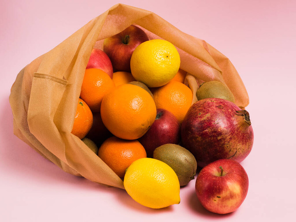 Mehrwegtasche mit Früchten auf rosa Hintergrund. Earth Day und Zero-Waste-Konzept - Foto, Bild
