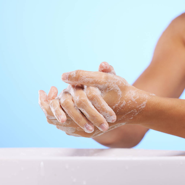 Σαπούνι, κορίτσι ή πλύσιμο χεριών σε στούντιο σε μπλε φόντο για ευεξία ή υγιή ενυδάτωση της επιδερμίδας. Μακέτα υγείας, ζουμ φροντίδας σώματος ή καθαρισμός γυναικών με υγρό για την υγιεινή ή την πρόληψη βακτηρίων. - Φωτογραφία, εικόνα