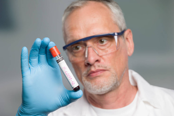doctor or scientist is handling a blood test tube in front of a laboratory - Foto, imagen
