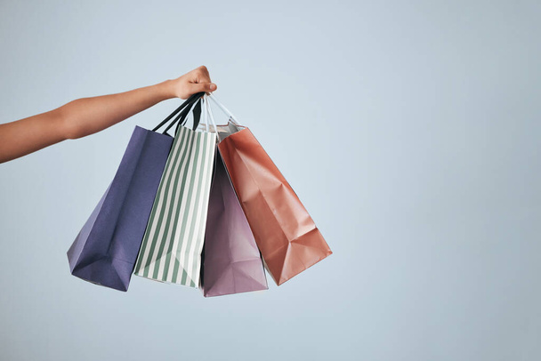 Hands, shopping bags and purchase on studio mockup for fashion, discount or sale against a gray background. Hand of shopper holding bag of gifts, present or luxury retail products on copy space. - Foto, immagini