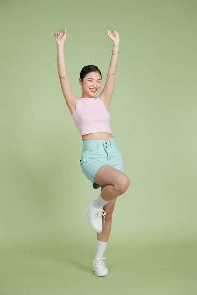 Full-length portrait of amazing asian girl posing with hands up - 写真・画像