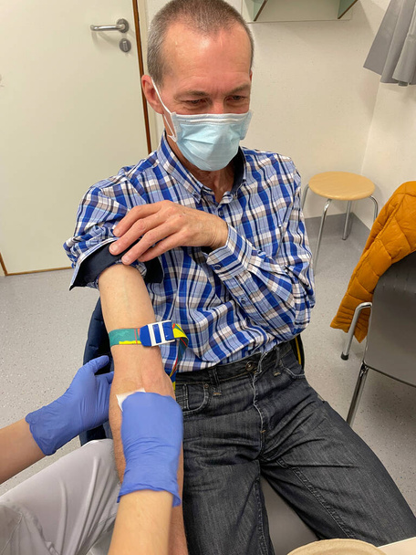 een verpleegkundige, arts of medisch technicus met blauwe handschoenen die een bloedmonster neemt van een patiënt in een ziekenhuis. Hoge kwaliteit foto - Foto, afbeelding