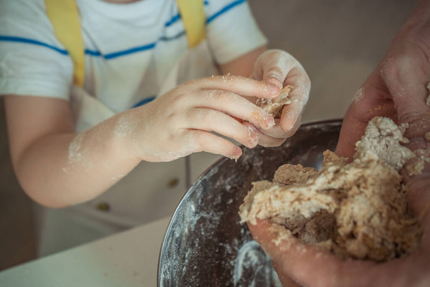 A child with apron is making a dough for cake, close-up - Fotó, kép