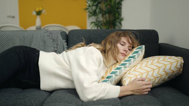 Nuori blondi nainen makaa sohvalla nukkumassa kotona - Valokuva, kuva