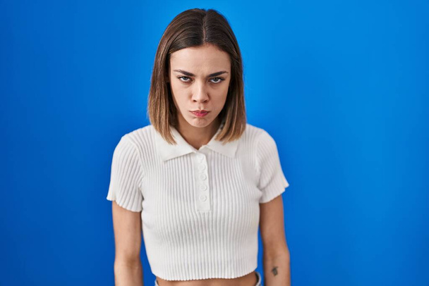 Hispanic woman standing over blue background skeptic and nervous, frowning upset because of problem. negative person.  - Photo, Image
