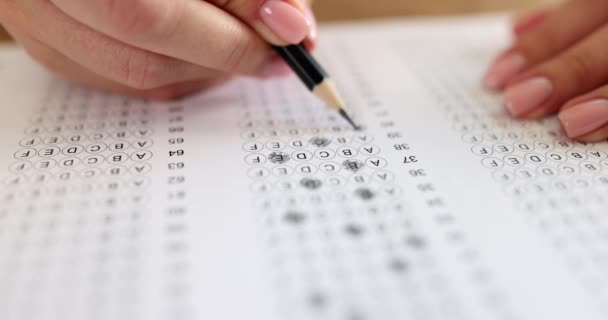 Vrouw doorgestreept juiste optie van test op examen papier blad met potlood. Vrouwelijke student met nette manicure ondergaat test in college slow motion - Video