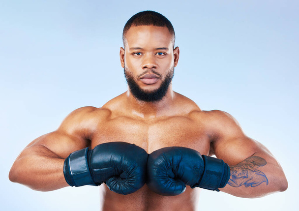 Gloves, boxing and portrait of a serious black man isolated on a blue background in studio. Ready, fitness and an African boxer looking focused for training, cardio challenge or a fight on a backdrop. - Photo, Image