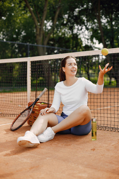 Woman sitting by net on tennis court. Having a rest after game. Hobbies, sports concept. - Foto, immagini