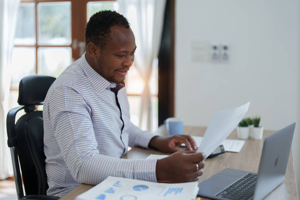 Американський африканець середнього віку, який використовує комп'ютерний ноутбук з плануванням роботи над фінансовим документом, податком, обміном, бухгалтерським обліком та фінансовим радником. - Фото, зображення