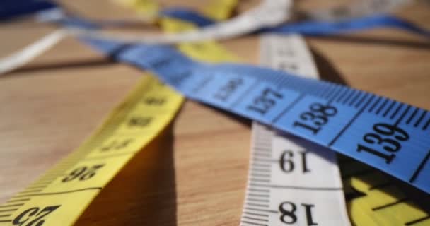 Šicí pásky měří různé typy metrik na dřevěném stole v ateliéru. Šatní potřeby na stole v dílně. Ruční nástroje na míru - Záběry, video