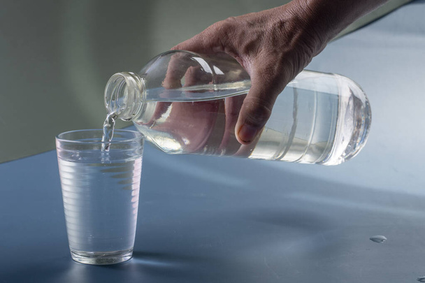 水のガラス充填人の詳細。青い背景の水分補給の概念は - 写真・画像