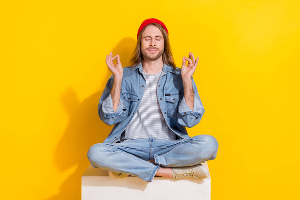 Photo of cool dreamy guy dressed jeans shirt smiling practicing yoga isolated yellow color background. - Foto, Bild