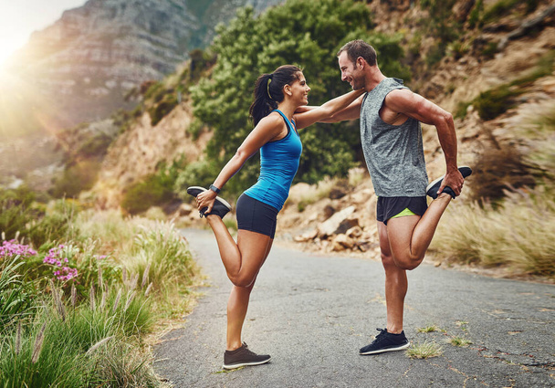 It is always better to stretch together. a young attractive couple training for a marathon outdoors - Foto, imagen
