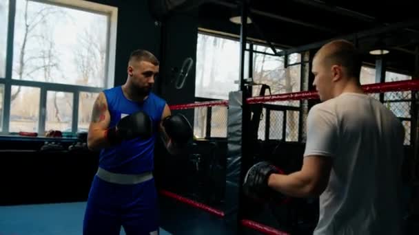 Boxeador practica sus golpes con su entrenador en el gimnasio de boxeo - Metraje, vídeo