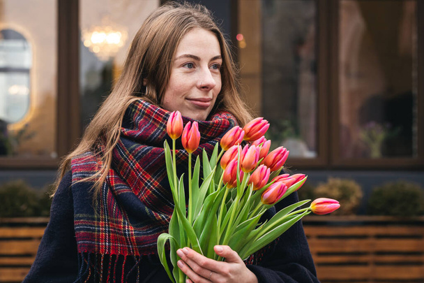 Close-up, bouquet of pink tulips in female hands, urban portrait, spring walk. - Foto, Imagen