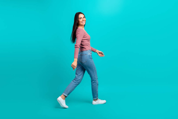 Full body profile photo of cheerful lovely lady walking empty space good mood isolated on teal color background. - Photo, image