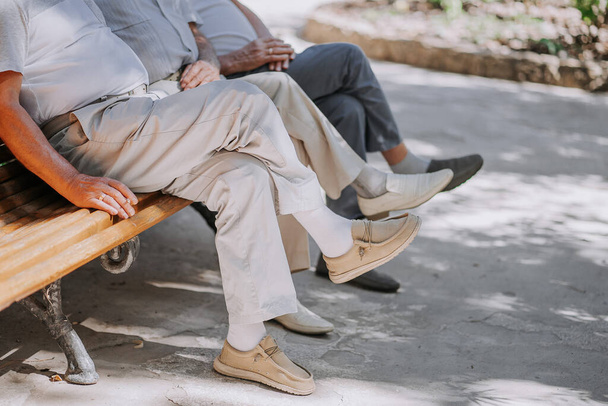 Pensioners grandfathers sit on bench and smoke cigarettes. Matured men, friends. High quality photo - Foto, Imagen