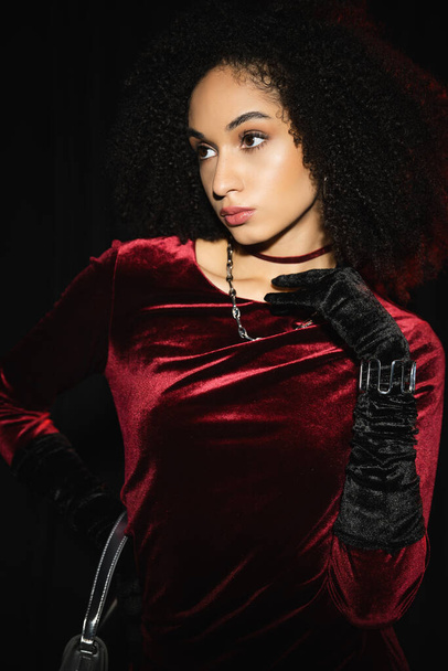 Stylish african american woman in velvet dress and glove isolated on black  - Foto, Imagen