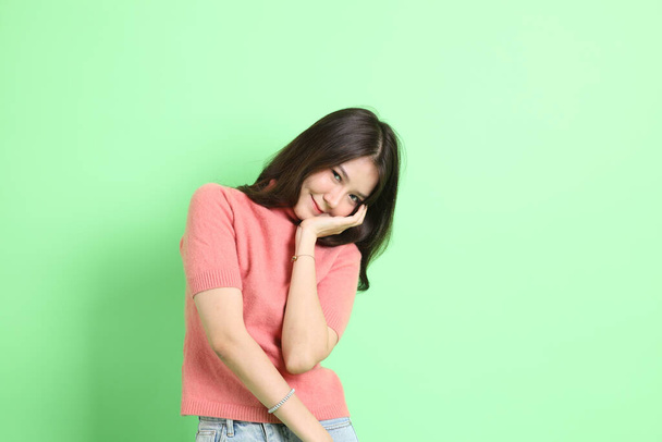 The young adult Asian woman with casual clothes with jeans standing on the green background. - Photo, image