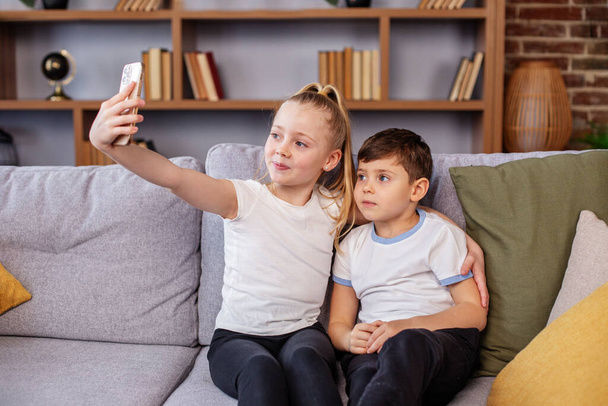 Rodzeństwo dzieci oglądające śmieszne media na smartfonie, grające w gry online, korzystające z aplikacji edukacyjnej w Internecie. Kontrola rodzicielska - Zdjęcie, obraz